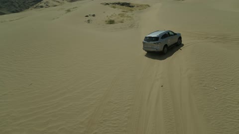 مغامرة سفاري على الكثبان الرملية في المملكة العربية السعودية, تصوير درون لسيارة ايسوزو ذات الدفع الرباعي الجبلية على رمال الصحراء الذهبية , التلال الرملية والتشكيلات والتكوينات الصخرية في الصحارى العربية, الأنشطة الترفيهية لقيادة السيارات في المناطق الصحراوية