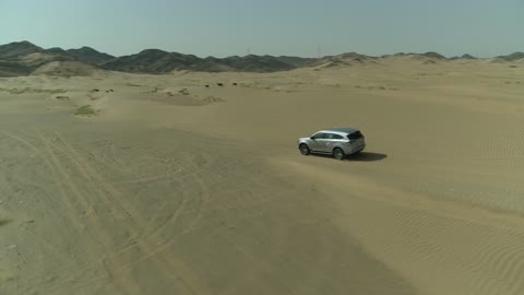 الأنشطة الترفيهية لقيادة السيارات في المناطق الصحراوية، مغامرة سفاري على الكثبان الرملية في المملكة العربية السعودية, تصوير درون لسيارة ايسوزو ذات الدفع الرباعي الجبلية على رمال الصحراء الذهبية , التلال الرملية والتشكيلات والتكوينات الصخرية في الصحارى العربية
