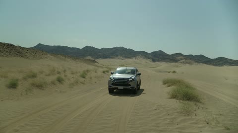Recreational activities for driving cars in desert areas, a safari adventure on the sand dunes in the Kingdom of Saudi Arabia, drone photography of an Isuzu off-road vehicle on the golden desert sands, sand hills, and rock formations in the Arab deserts.