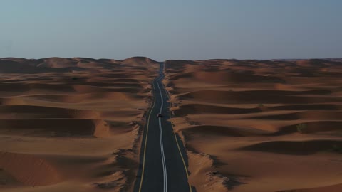 التلال الرملية والتشكيلات والتكوينات الصخرية في الصحارى العربية، الأنشطة الترفيهية لقيادة السيارات في المناطق الصحراوية،  الكثبان الرملية في المملكة العربية السعودية, تصوير درون لسيارة مرسيدس على طريق اسفلتي بين الصحراء و الرمال الصحراء الذهبية