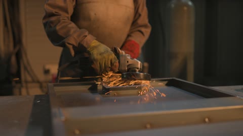 تجهيز وتوصيل الحديد بمعدات وأدوات لحامية خاصة، متابعة سير العمل في ورش الحدادة بمهارة وإتقان، ارتداء الزي الواقي للحماية من الشرار المتناثر في المعمل, عامل عربي خليجي سعودي يرتدي قناع الحماية والقفازات يقوم بلحام المعدن وصهره, وظائف ومهن صناعية للشباب السعودي