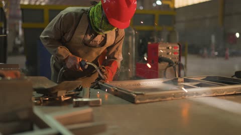 تجهيز وتوصيل الحديد بمعدات وأدوات لحامية خاصة، متابعة سير العمل في ورش الحدادة بمهارة وإتقان، ارتداء الزي الواقي للحماية من الشرار المتناثر في المعمل, عامل عربي خليجي سعودي يرتدي قناع الحماية والقفازات يقوم بلحام المعدن وصهره, وظائف ومهن صناعية للشباب السعودي