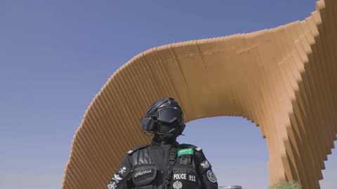The official police car, an Arab Gulf Saudi officer from the rapid intervention forces () wearing a black military uniform, maintaining security and safety, standing upright and disciplined, the police forces in the Kingdom of Saudi Arabia.