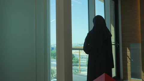 العمل في بيئة مريحة، تصوير من الخلف لموظفة عربية خليجية سعودية تقف بأيدي متقاطعة في شركة، الاناقة والاهتمام بالمظهر الخارجي، مهن ووظائف في شركات المملكة العربية السعودية