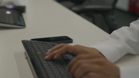 التواصل مع العملاء عن بعد، دمج التقنيات الحديثة و المتطورة مع العمل, مهن و أعمال مكتبية إدارية, تصوير مقرب ليد رجل  عربي خليجي سعودي يجلس داخل المكتب و يقوم بالكتابة على لوحة المفاتيح, إرسال بريد الكتروني عبر الحاسوب