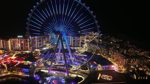 الأبراج وناطحات السحاب والمنشآت المطلة على البحر، تصوير درون لعجلة عين دبي في الامارات العربية المتحدة في وقت الليل، الوجهة البحرية على ساحل الخليج العربي، الفن الهندسي المعماري للمناطق والمعالم الترفيهية المشهورة