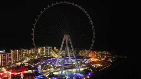 الأبراج وناطحات السحاب والمنشآت المطلة على البحر، تصوير درون لعجلة عين دبي في الامارات العربية المتحدة في وقت الليل، الوجهة البحرية على ساحل الخليج العربي، الفن الهندسي المعماري للمناطق والمعالم الترفيهية المشهورة