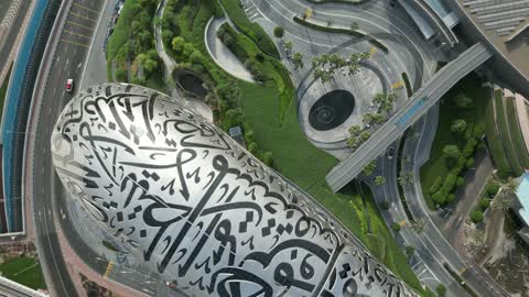 The architectural engineering art of the streets in the United Arab Emirates, the focus on planting trees and wide spaces, the Emirati future vision 2031, drone photography of the Museum of the Future in Dubai, the distinctive designs of towers and skyscrapers in a modern style, improving and developing infrastructure.