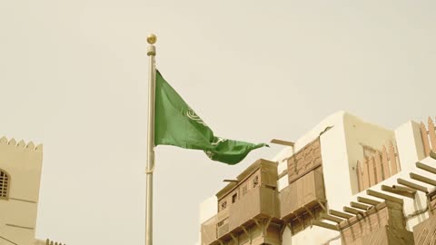 Love for the homeland and appreciation of national identity, famous tourist landmarks in the city of Jeddah, the flagpole of the Kingdom of Saudi Arabia waving in the historic city of Jeddah, the celebration of Saudi National Day, the old rawashin in the historic city of Jeddah with ancient Arab and Islamic architectural design.