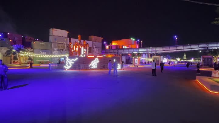 An enjoyable family and youth experience as part of the Riyadh Season events, nighttime atmosphere in the outdoor activities area, Soundstorm Middle Beast Festival in the Binban area of Riyadh, December 13, 2025, in the Kingdom of Saudi Arabia, strong blue lighting extending over the open path, visitors strolling through a fun and entertaining atmosphere.