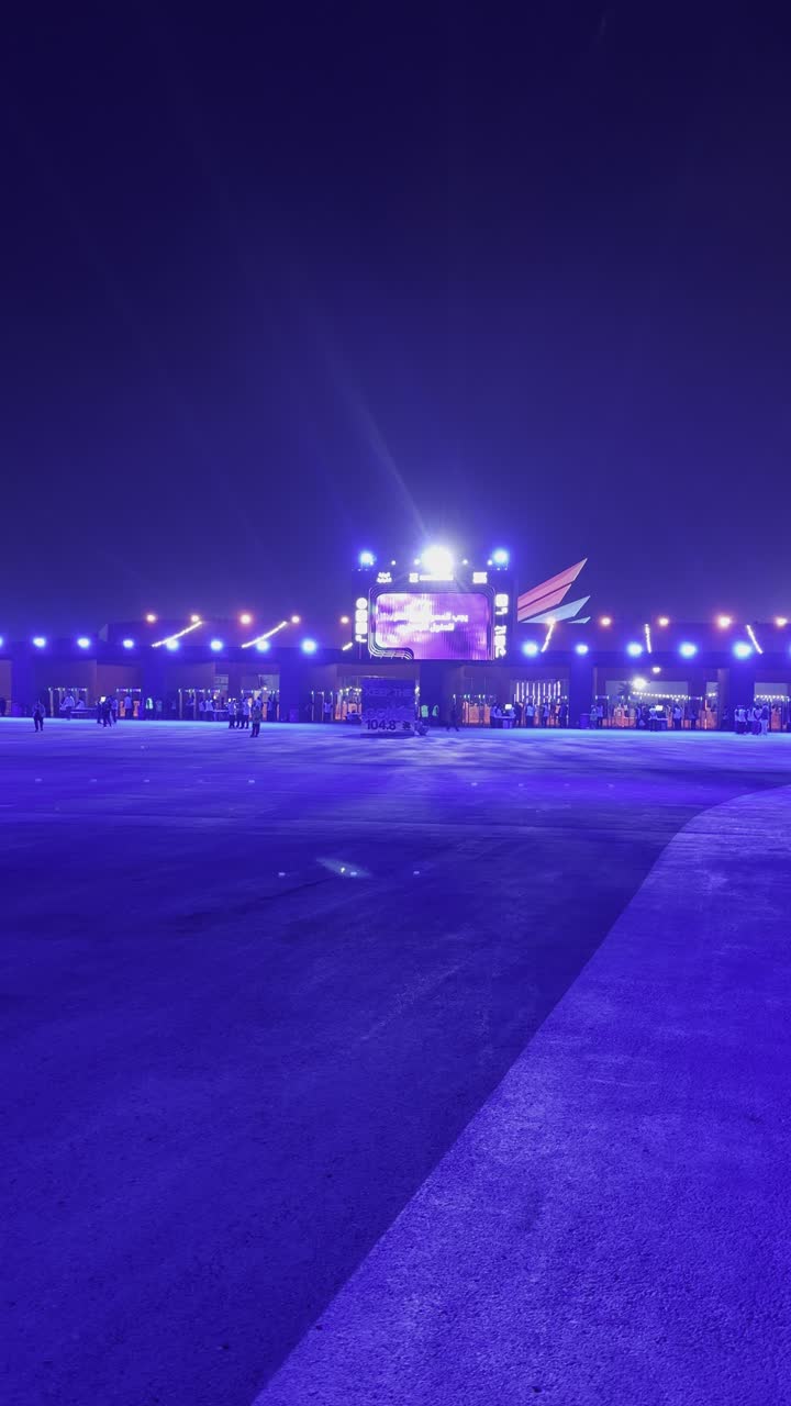 A strong blue light extends over the open path, a nighttime atmosphere in the outdoor activities area, the Soundstorm Middle Beast Festival in the Banban area of Riyadh, December 13, 2025, in the Kingdom of Saudi Arabia. Visitors stroll through an atmosphere filled with fun and entertainment, a family and youth experience as part of the Riyadh Season events.
