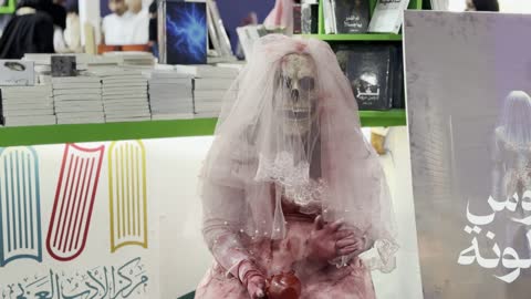 تصوير لمجسم يرتدي فستان زفاف وردي اللون، أداة ترويجية لرواية بعنوان "عروس برشلونة"، مركز الأدب العربي، معرض الكتاب الدولي في جدة 16 من ديسمبر 2025 ، المعالم والأماكن السياحية الثقافية المشهورة فى المملكة العربية السعودية، استقطاب وجذب السياح من أنحاء العالم ، فعاليات موسم الرياض