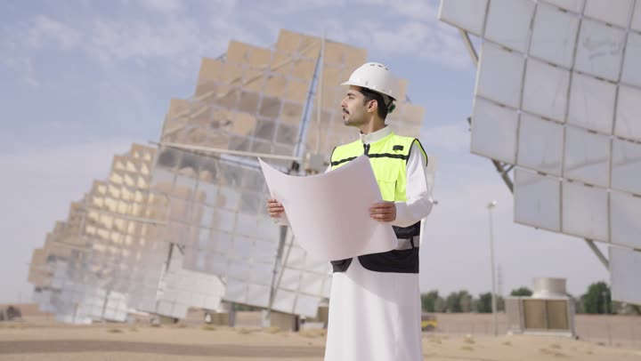 النظر الى شىء ما, الرقابة على المشروع الهندسي, مهندس عربى خليجى سعودى يمسك مخطط و تصميم هندسى , إرتداء خوذة وسترة الحماية, مهن ووظائف سعودية، محطات الطاقة الشمسية