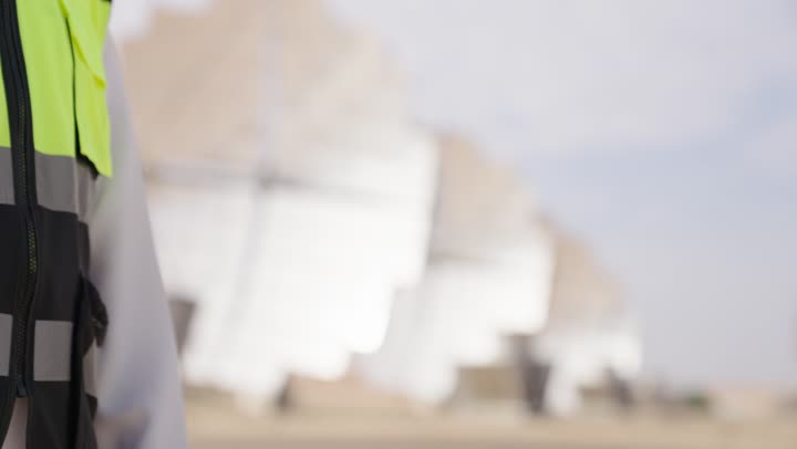Greeting, close-up shot of the hands of two Arab Gulf engineers from Saudi Arabia overseeing solar power stations shaking hands, wearing safety vests, supervising the work, solar power systems, exchanging expertise and opinions among colleagues.
