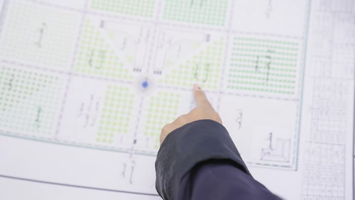 تصوير من الخلف لمهندس عربي خليجي سعودى يرتدى سترة وخوذة الحماية يحمل المخطط الهندسى و يتناقش مع زميلته حول المشروع في موقع البناء، مفهوم ادارة المشاريع الهندسية، دراسة المخطط على ارض الواقع، مهنة ووظيفة هندسية،