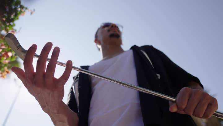 الاستعداد للعب والتنافس، تصوير مقرب ليد رجل عربي سعودي خليجي يرتدي الزي الكاجوال يضرب بكفه عصا الجولف عدة مرات، التسليه والترفيه بالالعاب الحركيه في الهواء الطلق