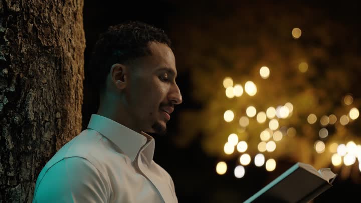 ثقافة التعلم الذاتي، الاستمتاع باوقات الفراغ ، قراءة الكتب بتمعن ، تصوير مقرب لرجل عربي خليجي سعودي يرتدي الثوب التقليدي  يجلس فى الهواء الطلق يحمل بيده كتاب تثقيفي ، إيماءات التركيز والاندماج ، قراءة الروايات والقصص