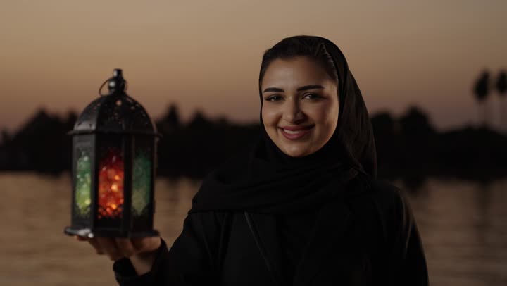 الإستعداد لقدوم شهر رمضان المبارك، المناسبات والأعياد الدينية، أجواء السكينة والروحانية، تصوير مقرب لامراة عربيه خليجيه سعودية محجبة ترتدي العباءة تقف فى الهواء الطلق تحمل بيدها فانوس معدني، العبادة والتقرب إلى الله