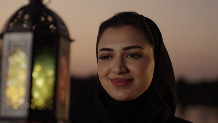 المناسبات والأعياد الدينية، أجواء السكينة والروحانية، تصوير مقرب لامراة عربيه خليجيه سعودية محجبة ترتدي العباءة تقف فى الهواء الطلق تحمل بيدها فانوس معدني، الإستعداد لقدوم شهر رمضان المبارك، العبادة والتقرب إلى الله