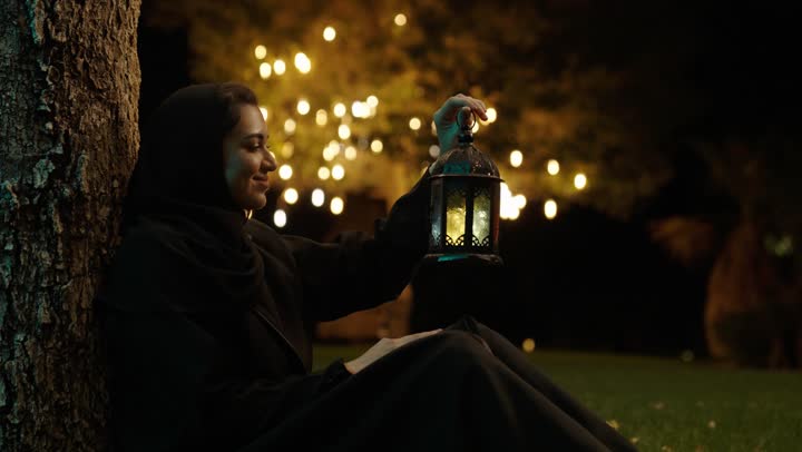 تعابير السعادة و السرور، الاحتفال بالمناسبات الدينية الإسلامية، البهجة بقدوم شهر الخير، التحضير لاستقبال رمضان المبارك, امراة عربية خليجية سعودية محجبة ترتدي العباءة تمسك بيدها فانوس معدني مزخرف