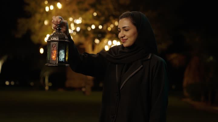 تعابير السعادة و السرور، البهجة بقدوم شهر الخير، التحضير لاستقبال رمضان المبارك,   امراة عربية خليجية سعودية محجبة ترتدي العباءة تمسك بيدها فانوس معدني مزخرف, الاحتفال بالمناسبات الدينية الإسلامية