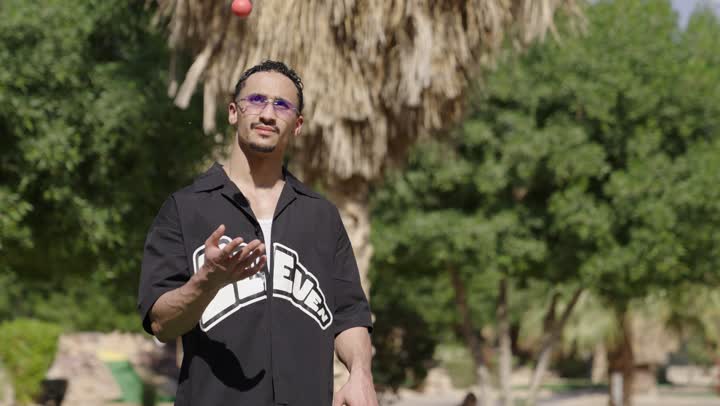 الترفيه بالأنشطة البدنية الخارجية، رجل عربي سعودي خليجي يرتدي الزي الكاجوال يضرب بكفه كره الجولف عدة مرات يمسك المضرب، الاستعداد للعب والتنافس، النظر للكاميرا بايماءات السعادة و السرور