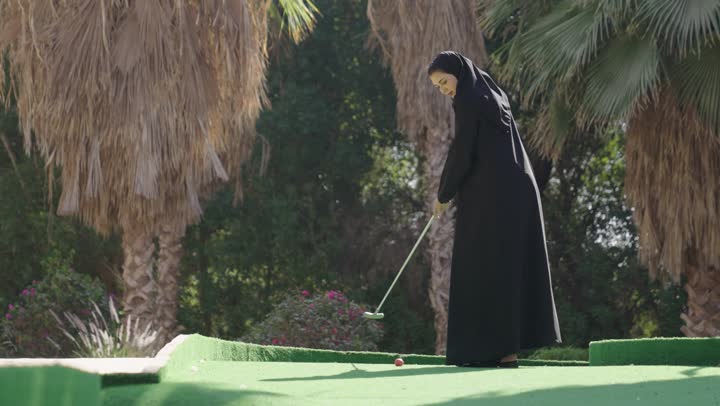 انشطه ترفيهيه رياضية، مفهوم اللياقة البدنية والرياضة الفردية، سيدة عربية خليجية سعودية ترتدي العباءة والحجاب تلعب كرة المضرب، ممارسة لعبة الغولف، ايماءات الفوز و الانتصار