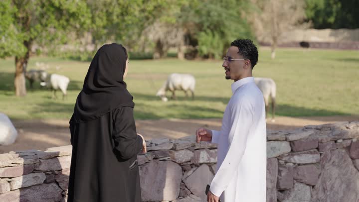 توثيق اللحظات السعيدة عبر الهاتف المحمول، زوجان عربيان خليجيان سعوديان يتجولان في احد الحدائق العامة يقومان بالتقاط صورة سيلفي من خلال الجوال، المشي والتنزه، نزهه في الهواء الطلق