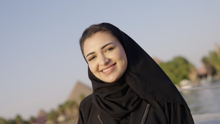 قضاء وقت ممتع فى الخارج ، امراة عربية خليجية سعودية ترتدي العباءة و الحجاب تجلس داخل المركب فى رحله نيلية، ايماءات السعادة و السرور ، عطله نهاية الاسبوع