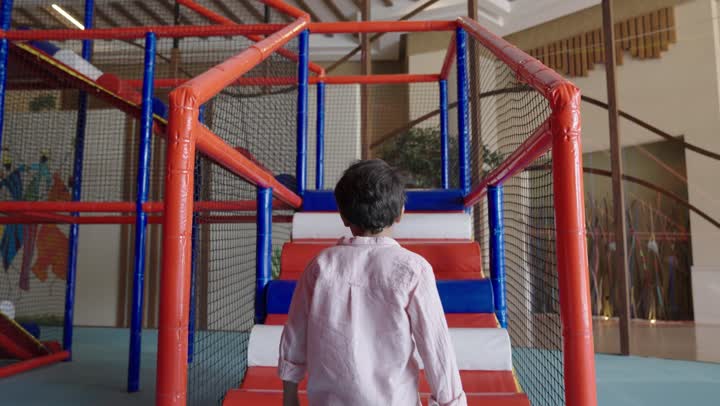 صعود الدرج اشارة لبدء اللعب الامن في مدينة الملاهي ,طفل عربي سعودي خليجي صغير يرتدي الزي الكاجوال يستعد لبداية لحظات من المتعة و السرور بين الالعاب العالية