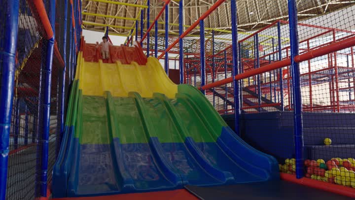 طفل عربي خليجي سعودي يرتدي الزي الكاجوال يشعر بالسعادة و المرح اثناء التزلج على الزحلوقة ,تقضية وقت عائلي لطيف بامان و سلامة في مدينة الملاهي , الاستمتاع باللعب في مدينة الملاهي