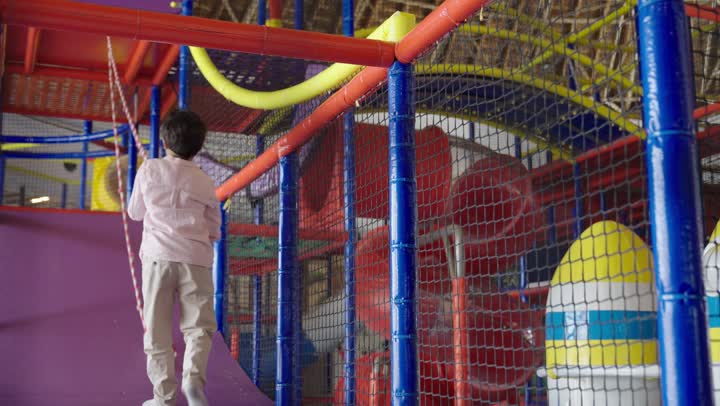 قضاء اوقات مسلية مع تعلم مهارات حياتية جديدة ,الاصرار على الوصول للقمة مع عدم الاستسلام ,طفل عربي سعودي خليجي يرتدي الزي الكاجوال يتسلق الحبل , الاستمتاع باللعب في مدينة الملاهي