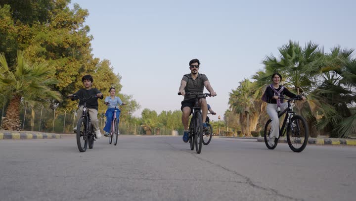 الوالد بجانب بناته الصغار يستمتعون بركوب الدراجة الهوائية باحترافية ,ايماءات السعادة و الفرحة وسط الطبيعة الساحرة , مفهوم الامان العائلي و الشعور بالطمأنينة