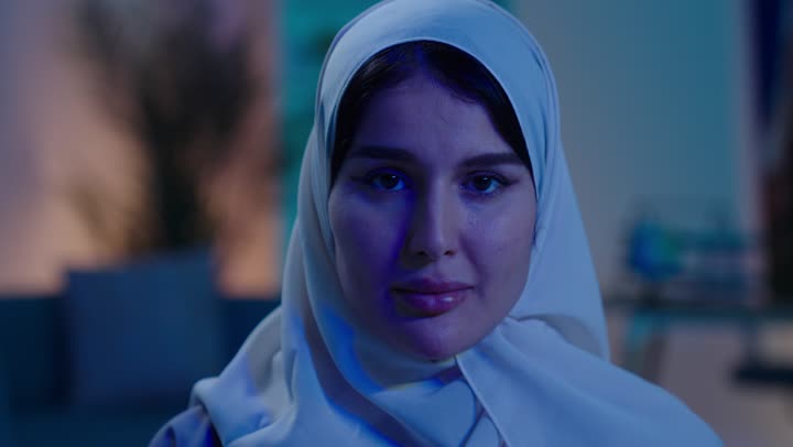 التفاعل والاندماج مع ألعاب الفيديو ،اجهزة وتقنيات الكترونية حديثة ترفيهيه, ايماءات الفوز و السعادة ، قضاء وقت ممتع ومسلي، ، شابة عربية خليجية سعودية ترتدي العباءة و الحجاب تجلس  على كرسي تحمل عصا التحكم