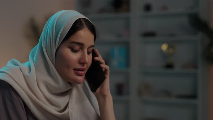 الاستمتاع بتناول المشروب المفضل، اجراء مكالمة هاتفية عبر الهاتف المحمول، ايماءات السعادة والسرور، دمج التقنيات الحديثة بالحياة اليومية، تصوير مقرب لامرأة عربية خليجية سعودية ترتدي العباءة و الحجاب تقوم بالتواصل مع الاهل والاصدقاء عبر الجوال