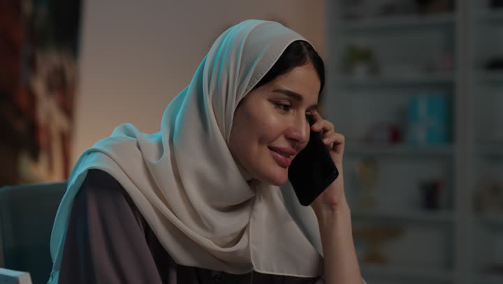 Gestures of happiness and joy, making a phone call via a mobile phone, integrating modern technologies into daily life, a close-up shot of a Saudi Gulf Arab woman communicating with family and friends via mobile.