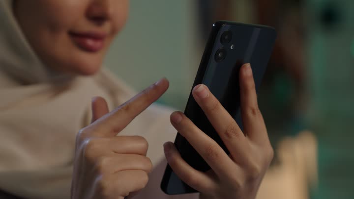 استخدام التقنية والتكنولوجيا والاجهزة الحديثة، تصوير مقرب ليد شابة عربية خليجية سعودية محجبة ترتدي العباءة تقوم بالنقر على شاشة الهاتف المحمول، تصفح مواقع التواصل الاجتماعي