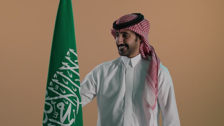اظهار الحب والولاء للمملكه، احياء ذكرى اليوم الوطني السعودي 23 سبتمبر، بورتريه لرجل عربي خليجي سعودي مبتسم يرتدي الثوب و الشماغ يحمل شعار السعودية للاحتفال في يوم العلم 11 مارس، مناسبات وطنية شعبيه، خلفية بنية