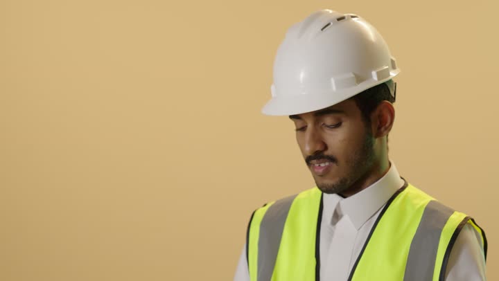 الأجهزة التقنية الحديثة، التأكد من سير الأعمال بالشكل المطلوب والصحيح، بورتريه مقرب لمهندس عربي خليجي سعودي يرتدي الثوب الابيض والخوذة وسترة الحماية باستخدام الجهاز اللوحي، تدوين و تسجيل الملاحظات, كتابة آخر المستجدات حول المشروع، خلفية بيج