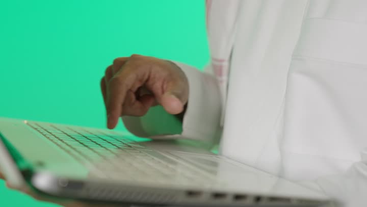 النقر على لوحة المفاتيح، صناعة المحتويات النصية، مفهوم ادخال البيانات، بورترية مقرب ليد رجل عربي خليجي سعودي يقوم بالكتابة على جهازاللابتوب، دمج التكنولوجيا الحديثة بالحياة العملية، خلفية خضراء، كروما