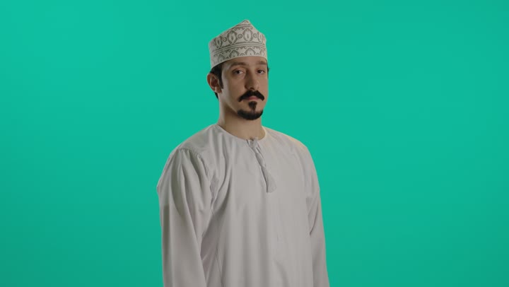 تعابير وجه غاضبة , رجل عربي خليجي عماني يرتدي الدشداشة البيضاء و الكمة المطرزة يفتح قبضة الكف امام الكاميرا اشارة على التوقف عن فعل شئ ما , علامة ممنوع الاقتراب او التقدم اكثر