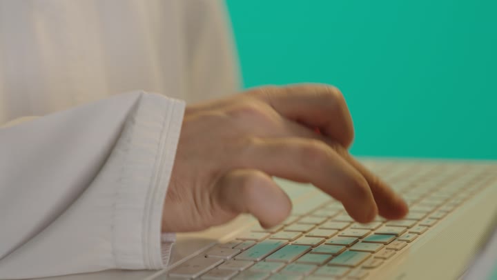 النقر على لوحة مفاتيح الحاسوب بسهولة واحترافية ,رجل عربي خليجي عماني يرتدي دشداشة بيضاء يحمل الحاسب المتنقل ,