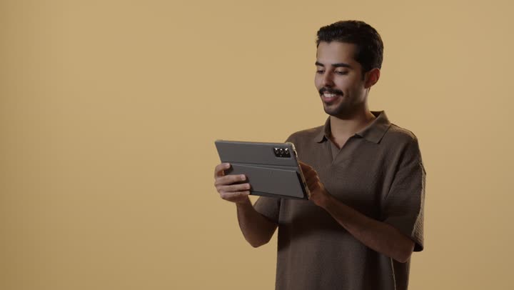 النظر الى الجهز اللوحي بسعادة بالغة , رجل عربي خليجي سعودي يرتدي الزي الكاجوال يحمل الجهاز التقني المتطور , ارسال الرسائل النصية بسهولة مع التطبيقات المختلفة