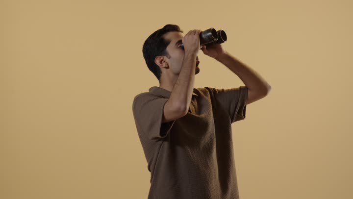 رجل عربي خليجي سعودي يرتدي الزي الكاجوال يستخدم المنظار المقرب لرؤية شئ ما في السماء البعيدة , تعابير الدهشة و الفتون , ايماءات السعادة و الابتسامة على الوجه