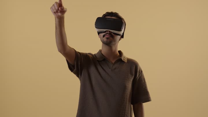 Finger movement in the air, moving and zooming images, an Arab Gulf Saudi man wearing casual attire and glasses to simulate the real world in the virtual world.