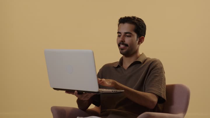 البقاء متصل مع العائلة و الاصدقاء , تعابير السعادة و الفرحة , رجل عربي خليجي سعودي يرتدي الزي الكاجوال  يحمل جهاز الحاسوب , الكتابة باحترافية و اتقان