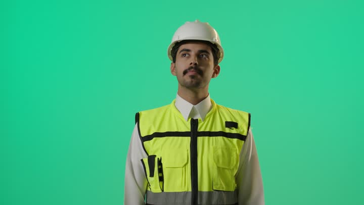 استخدام الادوات الخاصة بالتواصل في مواقع البناء , مهندس عربي خليجي سعودي يرتدي اليونيفورم الخاص بالمهندسين , التواصل مع باقي افراد المشروع باستخدام جهاز اللاسلكي , النظر الي شئ بعيد بالمنظار المقرب