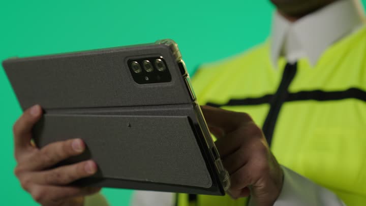 Accomplishing tasks in a short time and saving time and effort, a Gulf Arab Saudi engineer wearing the uniform specific to engineers at work sites, using a tablet in engineering, close-up shot.