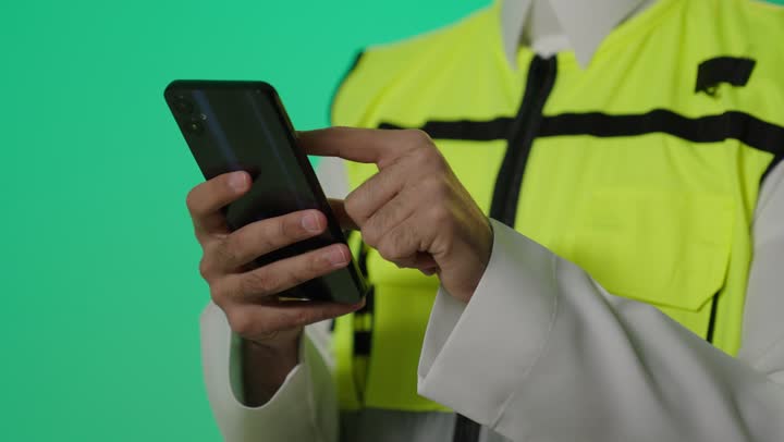 تصفح مواقع التواصل الاجتماعي للاطلاع على التطورات الجديدة في عالم الهندسة , مهندس عربي خليجي سعودي يرتدي خوذة الامان و الصديري العاكس للضوء يحمل الهاتف المحمول  لزيادة العلم و الخبرة