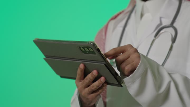 ارسال الرسائل النصية و البريد الالكتروني بين الافراد و الشركات , طبيب عربي خليجي سعودي يرتدي المعطف الطبي الابيض يحمل الجهاز اللوحي يتواصل مع باقي الاصدقاء , السرعة في وصول المعلومة الجديدة